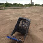 Sometimes large garbage items, such as shopping carts, wash down into the Arkansas River outside of Tulsa, Oklahoma. The Oral Roberts towers are in the background.
