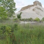 Twentieth century mining companies dumped huge piles of slag outside of Picher, on Quapah Native American land in northeast Oklahoma. The soil, water, and dust is now contaminated by lead so much that most people have left. The cliffs are not rock, but slag from mine tailings.