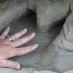Fossilized footprint of a small carnivorous dinosaur Acrocanthosaurus, which walked here in a shallow sea 110 million years ago. Human hand for comparison. Paluxy River, Dinosaur Valley State Park, Texas.