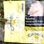 "Smoking causes 9 out of 10 lung cancers." A graphic cigarette pack thrown on the ground in Hoenheim, north of Strasbourg, France. Most cigarettes come from Germany, where they are cheaper because they are taxed less than in France. Germany is just over the bridge from Strasbourg. There are a lot of smokers in France, who seem undeterred by the images, and who also disproportionately throw litter on the ground. Was tut man? The sad man on this pack has had lung cancer surgery.