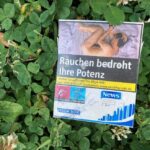 A graphic cigarette pack thrown on the ground in Hoenheim, north of Strasbourg, France. Most cigarettes come from Germany, where they are cheaper because they are taxed less than in France. Germany is just over the bridge from Strasbourg. There are a lot of smokers in France, who seem undeterred by the images, and who also disproportionately throw litter on the ground. Was tut man? The sad man on this pack has just had his "Potenz" (sexual potency) taken away by smoking.