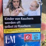 A graphic cigarette pack thrown on the ground in Hoenheim, north of Strasbourg, France. Most cigarettes come from Germany, where they are cheaper because they are taxed less than in France. Germany is just over the bridge from Strasbourg. There are a lot of smokers in France, who seem undeterred by the images, and who also disproportionately throw litter on the ground. Was tut man? The little kid is learning that it is OK to smoke because he sees his Mom doing it.