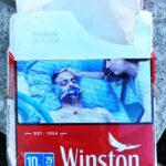 A graphic cigarette pack thrown on the ground in Hoenheim, north of Strasbourg, France. Most cigarettes come from Germany, where they are cheaper because they are taxed less than in France. Germany is just over the bridge from Strasbourg. There are a lot of smokers in France, who seem undeterred by the images, and who also disproportionately throw litter on the ground. Was tut man?