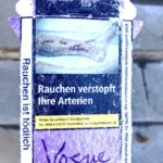 "Smoking clogs your arteries." A graphic cigarette pack thrown on the ground in Hoenheim, north of Strasbourg, France. Most cigarettes come from Germany, where they are cheaper because they are taxed less than in France. Germany is just over the bridge from Strasbourg. There are a lot of smokers in France, who seem undeterred by the images, and who also disproportionately throw litter on the ground. Was tut man? The picture shows arterial stitches on extremities.