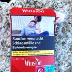 "Smoking causes strokes and disabilities," in German. A graphic cigarette pack thrown on the ground in Hoenheim, north of Strasbourg, France. Most cigarettes come from Germany, where they are cheaper because they are taxed less than in France. Germany is just over the bridge from Strasbourg. There are a lot of smokers in France, who seem undeterred by the images, and who also disproportionately throw litter on the ground. Was tut man? The sad woman has just lost her lover to a stroke.